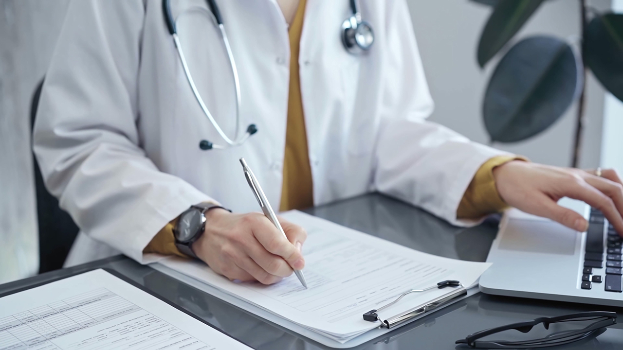 Doctor woman is working on laptop with medical reports. Healthcare professional reviews patient files and inputs data in a clinic setting. Medicine Doctor woman is working on laptop with medical reports. Healthcare professional reviews patient files and inputs data in a clinic setting. Medicine.